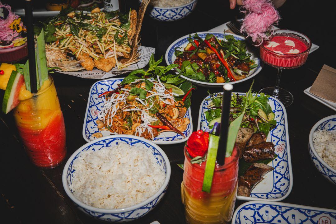 Plats of noodles and skewers on table