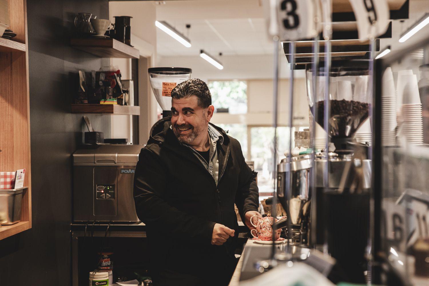 man standing in kitchen making tea