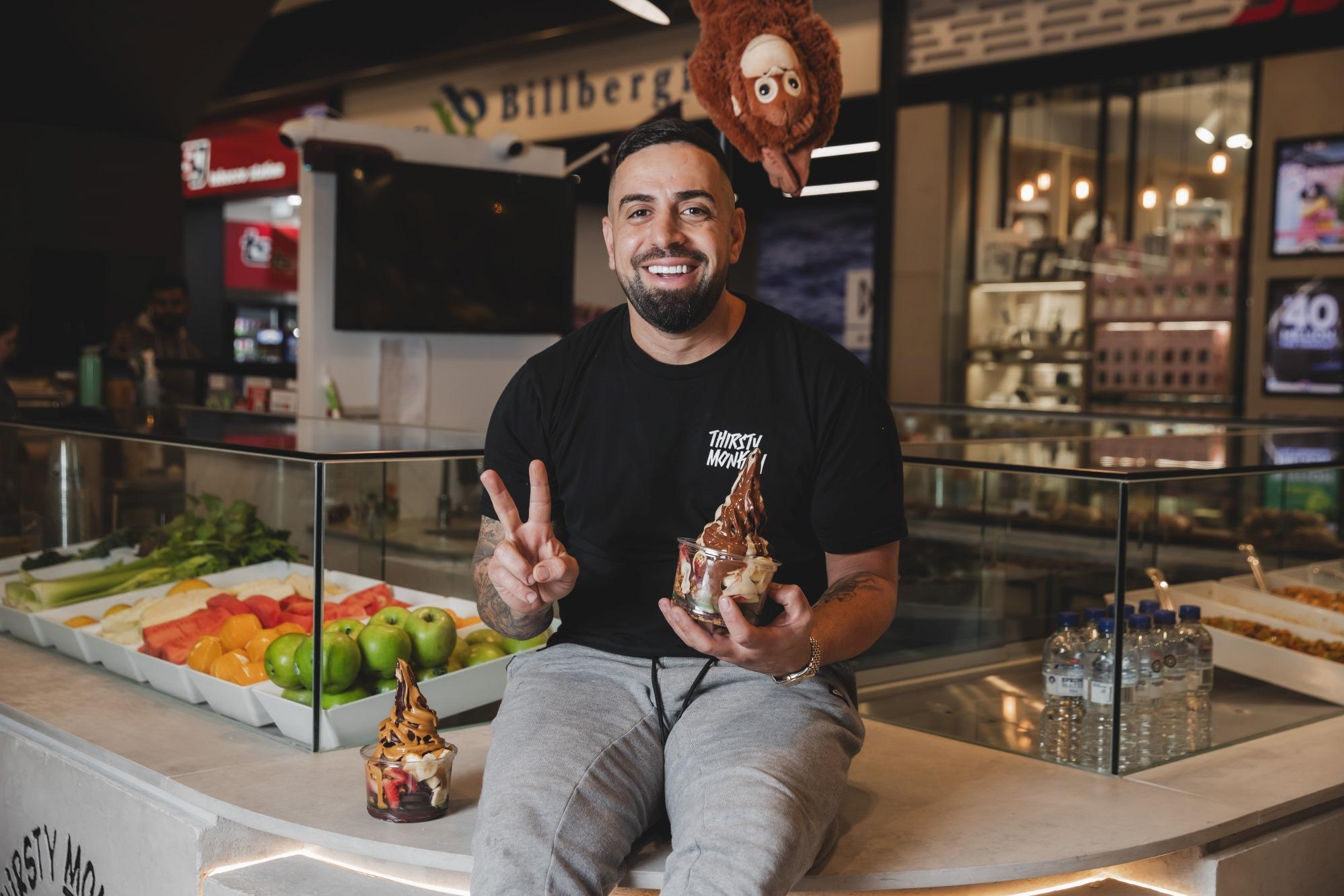 man sitting on a food counter holding an acai bowl