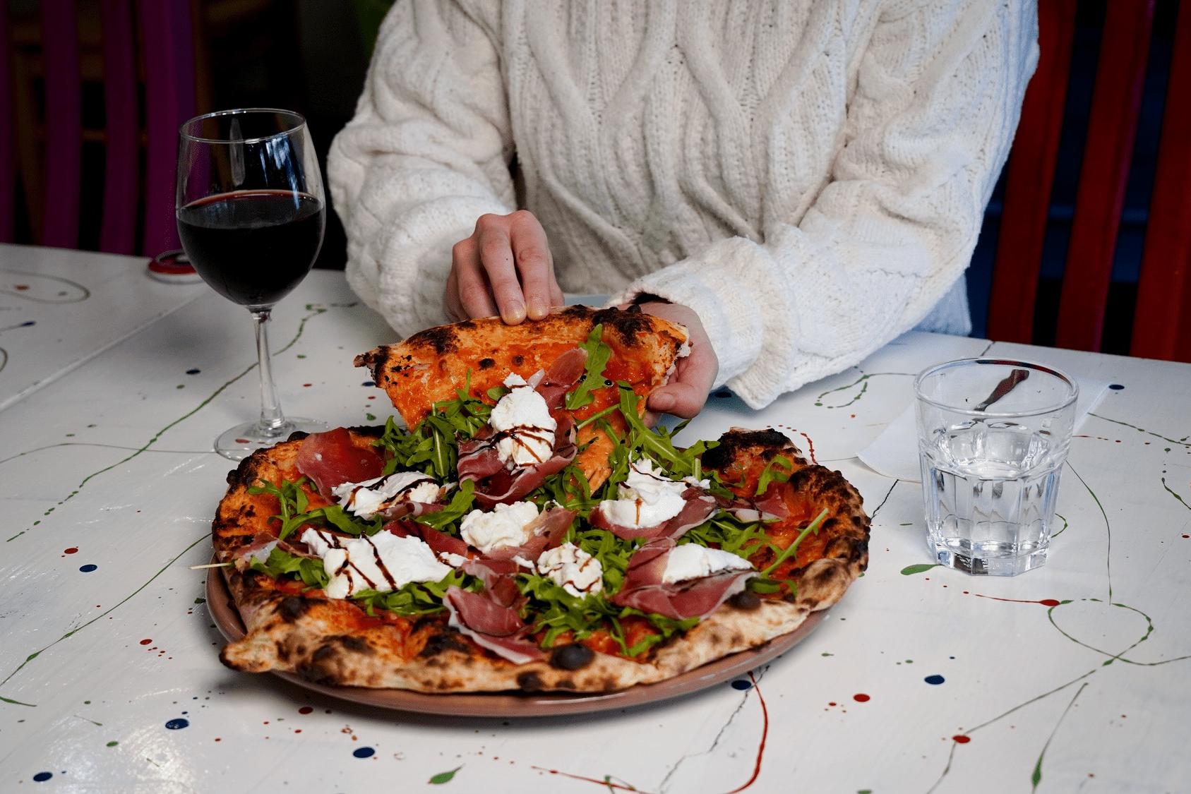 Person picking up a slice of pizza