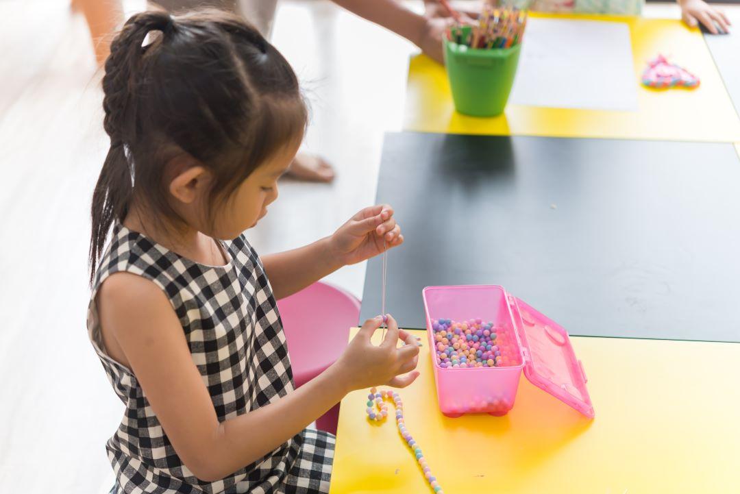 Little girl making bracelets