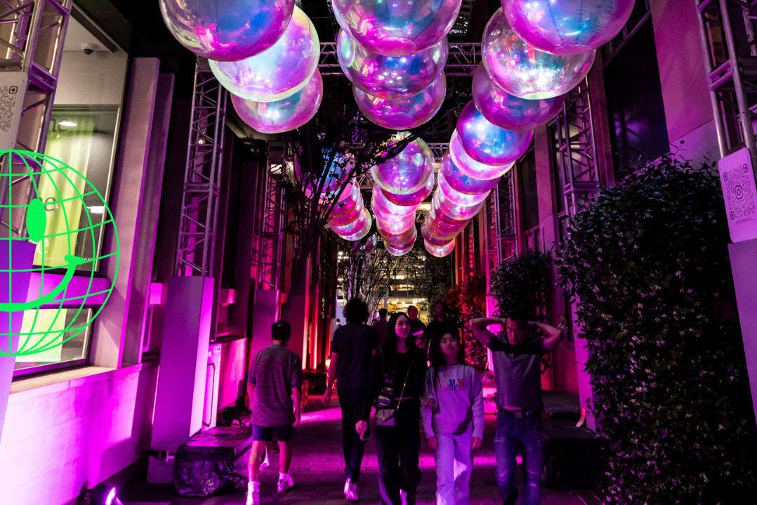 artwork hanging over an alleyway, pink lighting