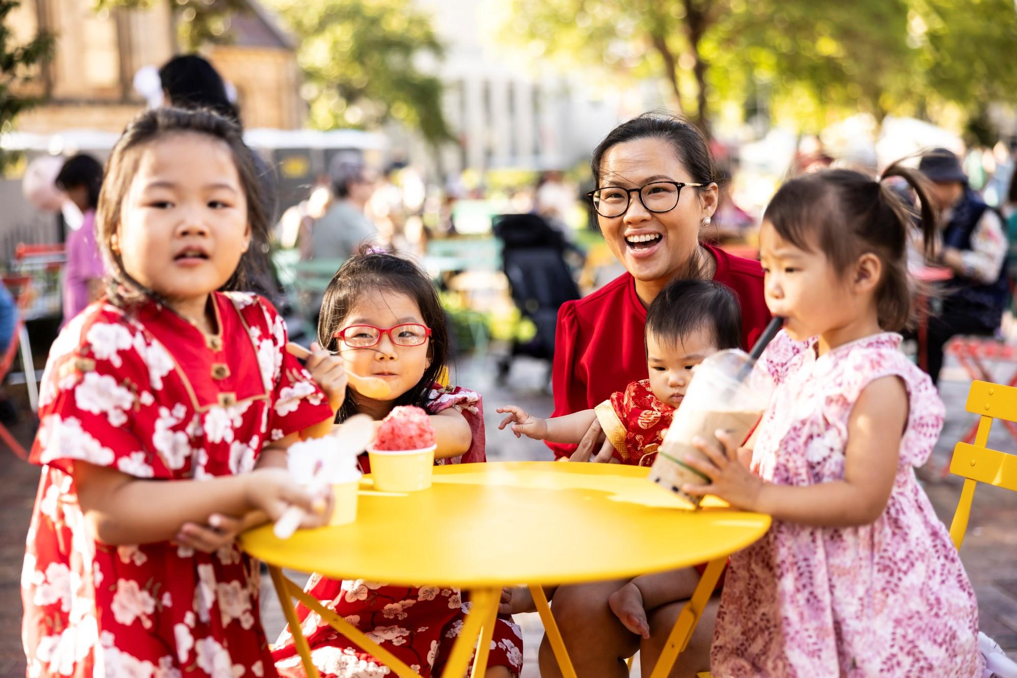 Family sitting around a yellow table eating food.