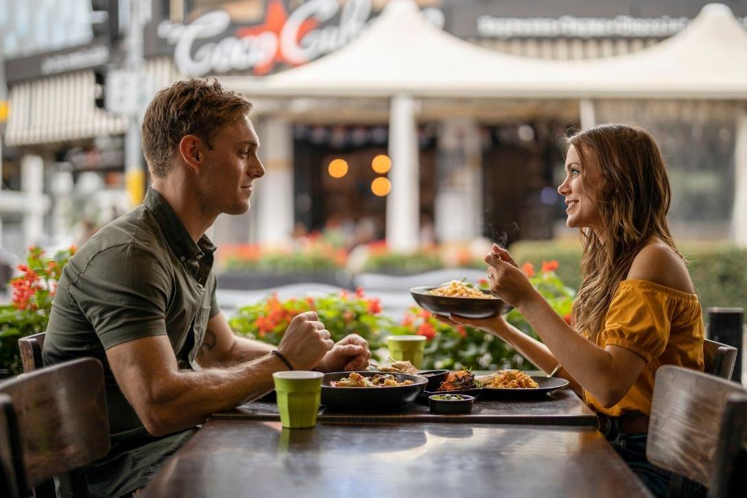 man and woman sitting at a restaurant sharing a meal