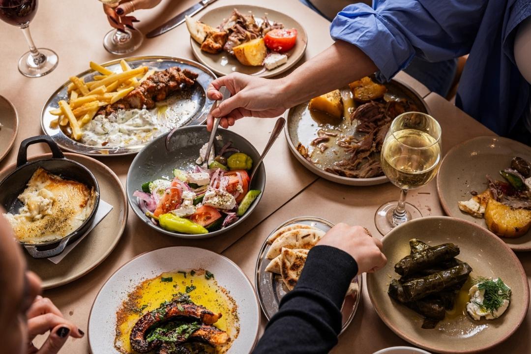 Table of greek salad, meat and drinks