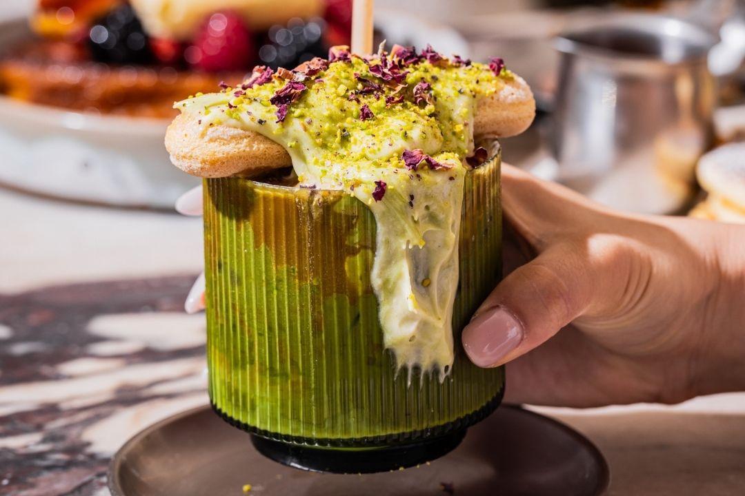 Glass of green matcha with overflowing cream 