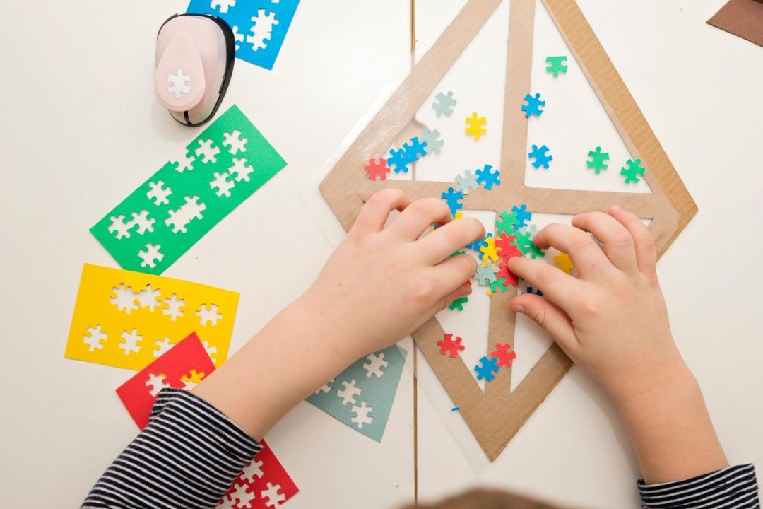 Child decorating a kite on a table