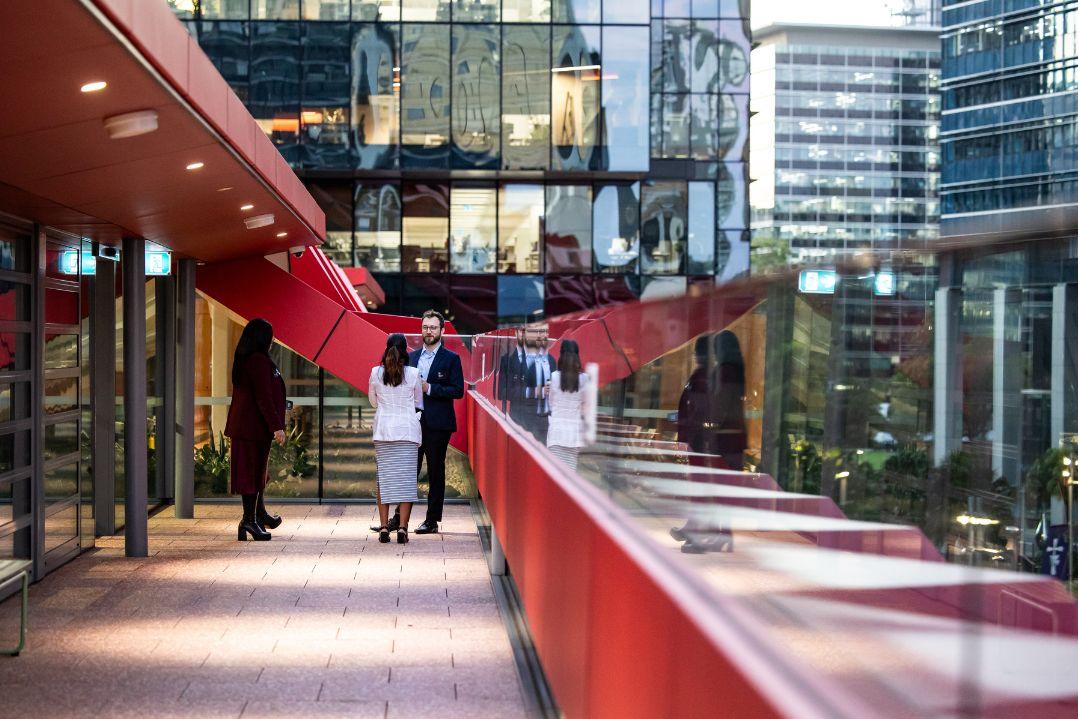 2 woman and a man talking at the top level of PHIVE overlooking high rise buildings