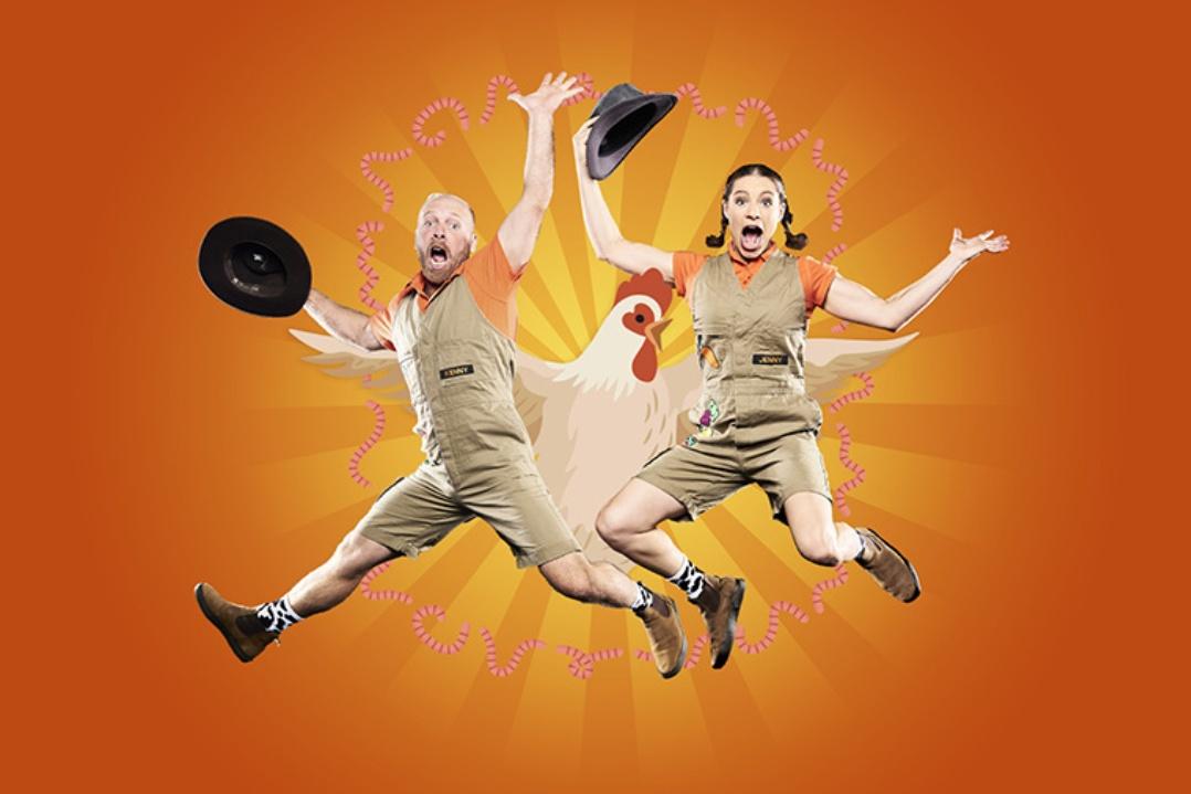 Three exuberant men in matching outfits leap joyfully against an orange background, each holding a black hat and radiating energy and excitement.