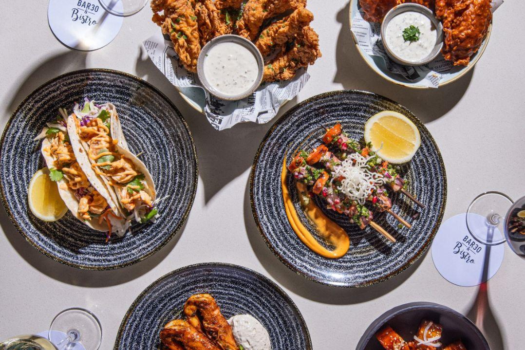 Top view of a dining table displaying plates of gourmet seafood, including lobster, fish, and clams, garnished with lemon slices and served with sauces.