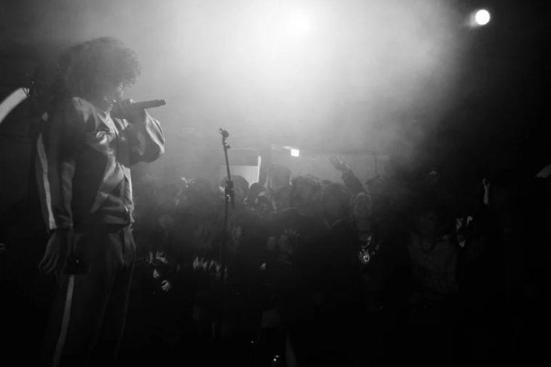 Three people in a row. Left: Man in black leather jacket, serious. Center: Woman in green dress, confident. Right: Man in red jacket, arms crossed.
