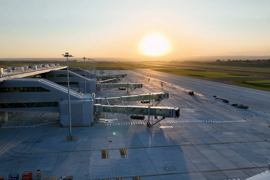 Sunset over a quiet airport with empty gates and long shadows on the tarmac.