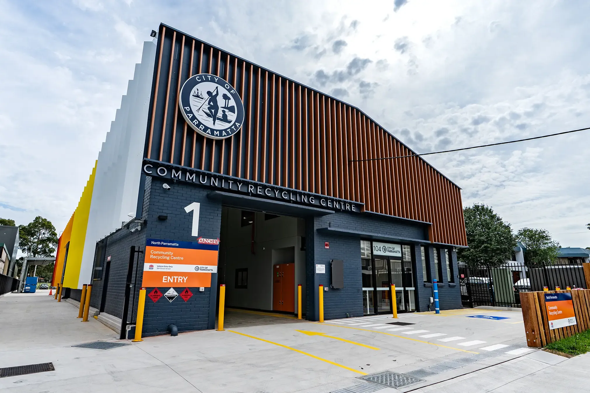 Community Recycling Centre with modern design features a large entryway, wooden paneling, and clear signage.