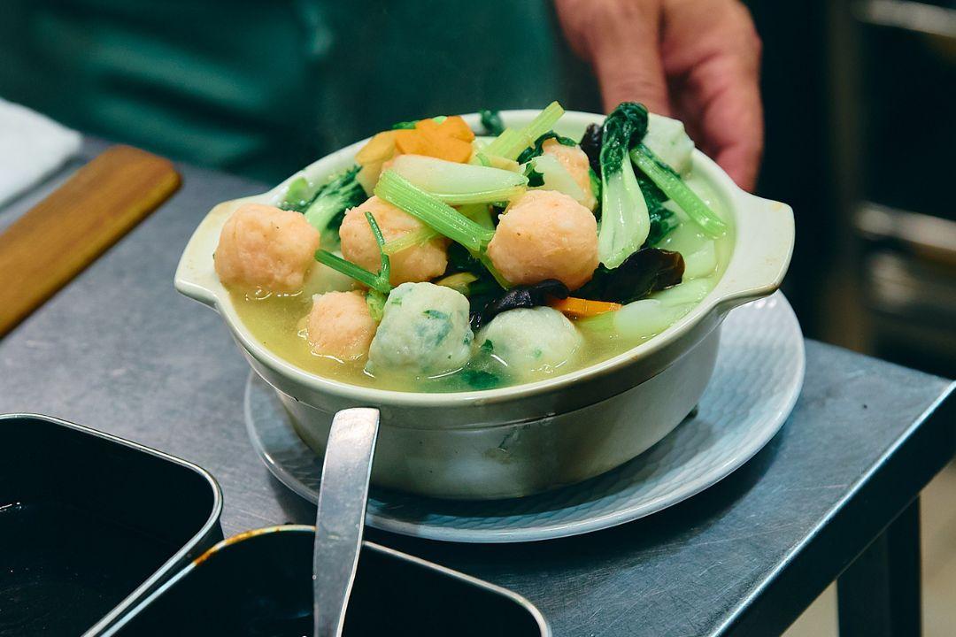A ceramic bowl filled with fish ball soup sits on a kitchen counter.
