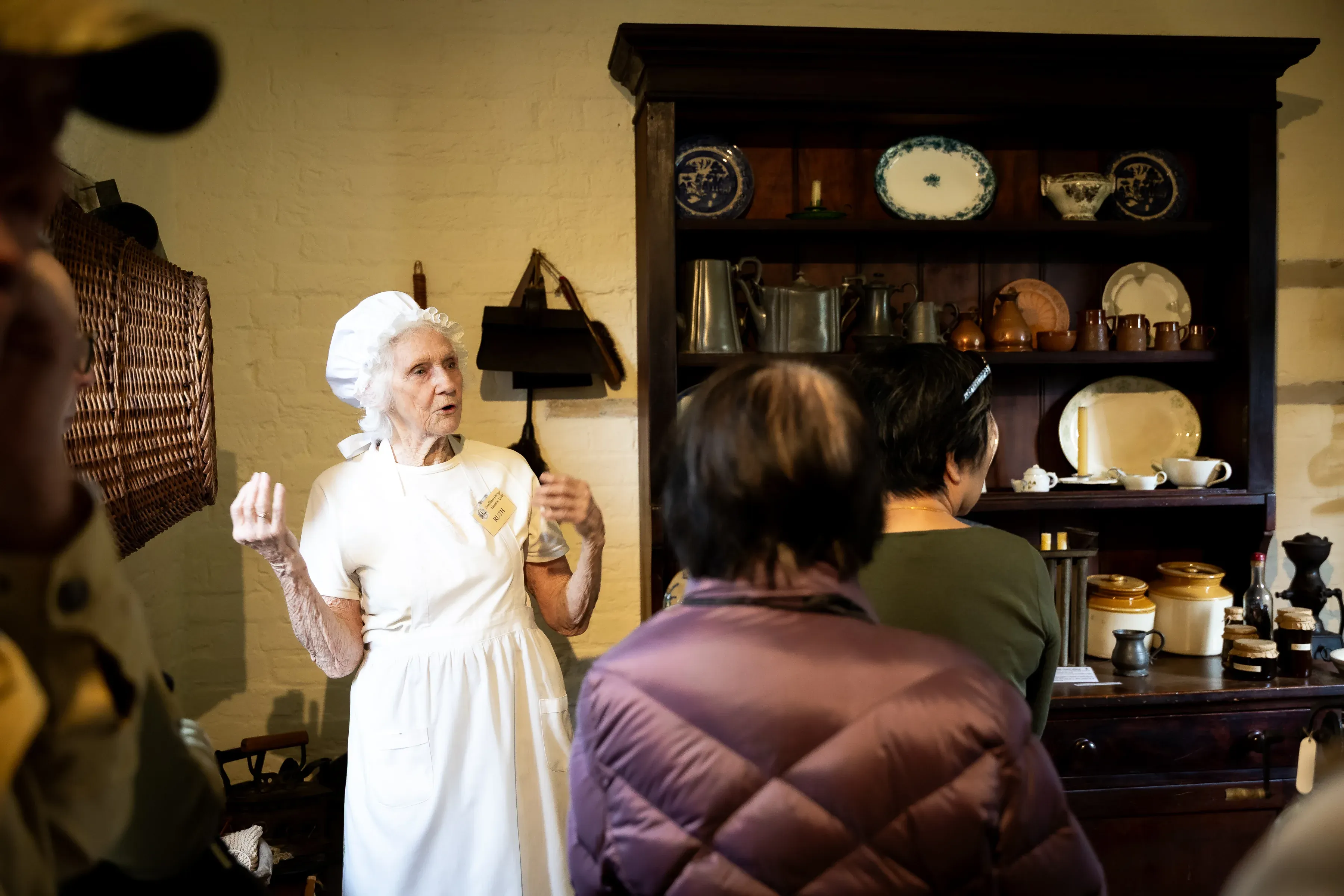 An interpreter dressed in period clothing speaks to a group of visitors inside a heritage building.