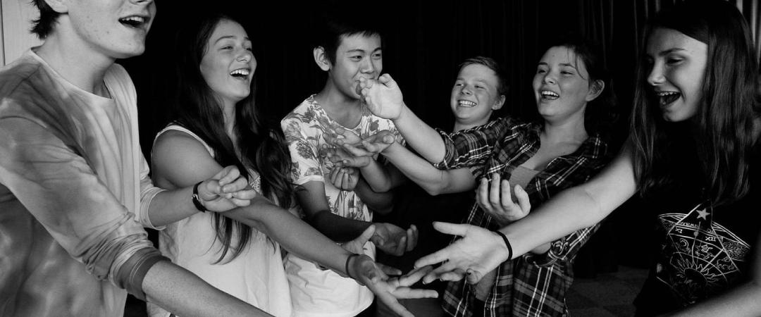 Teenagers with their hands outstretched and doing a performance together