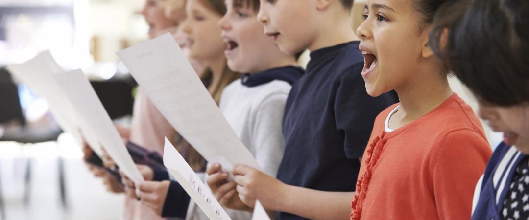 Kids singing together and holding a sheet of paper