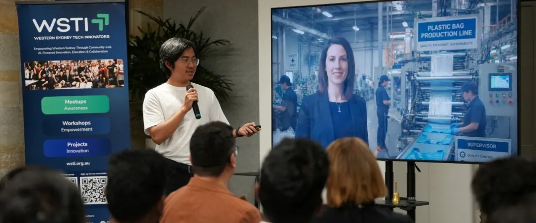 A presenter speaks to an attentive audience beside a screen showing a woman and a plastic bag production line during an informative WSTI workshop.