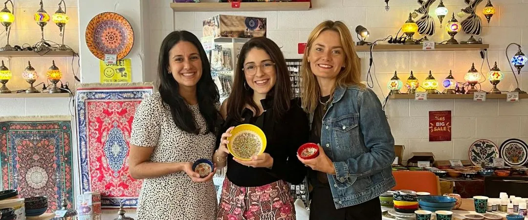 3 women standing in the middle with 3 bowls 