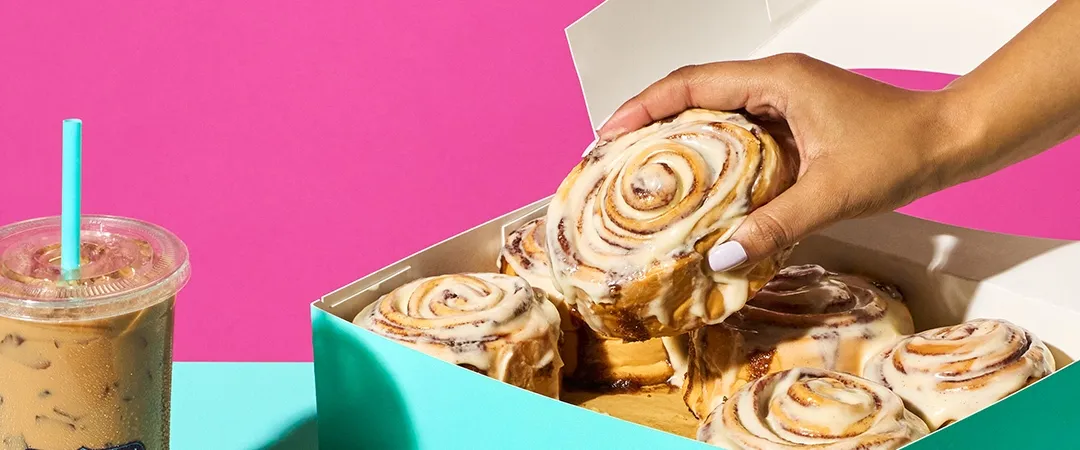 Hand pikcing up a cinnamon roll