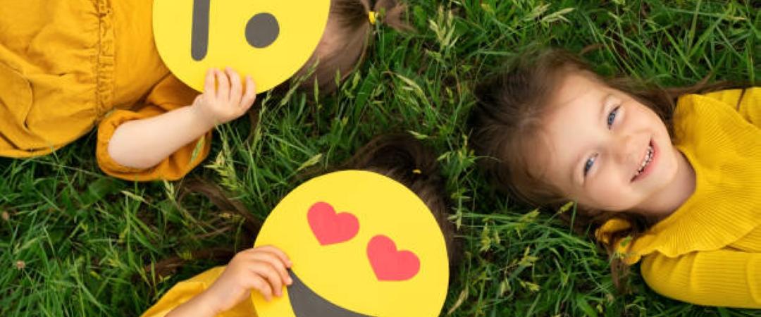 Children in yellow tshirts lying in the grass with yellow face masks