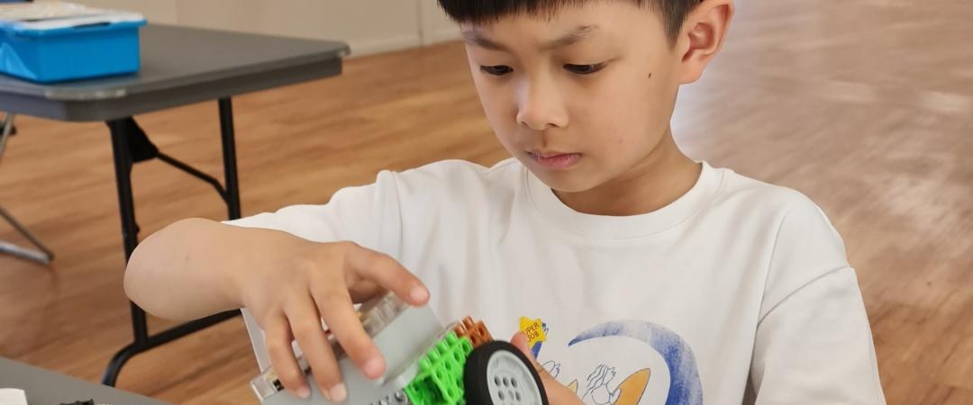 Boy in white tshirt holding mechanical toy