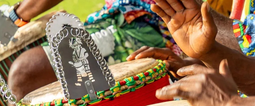 close up shot of hands on african drops wearing colourful printed clothing