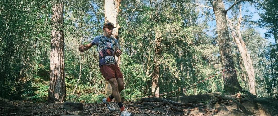 Man smiling running a race through a bush forest