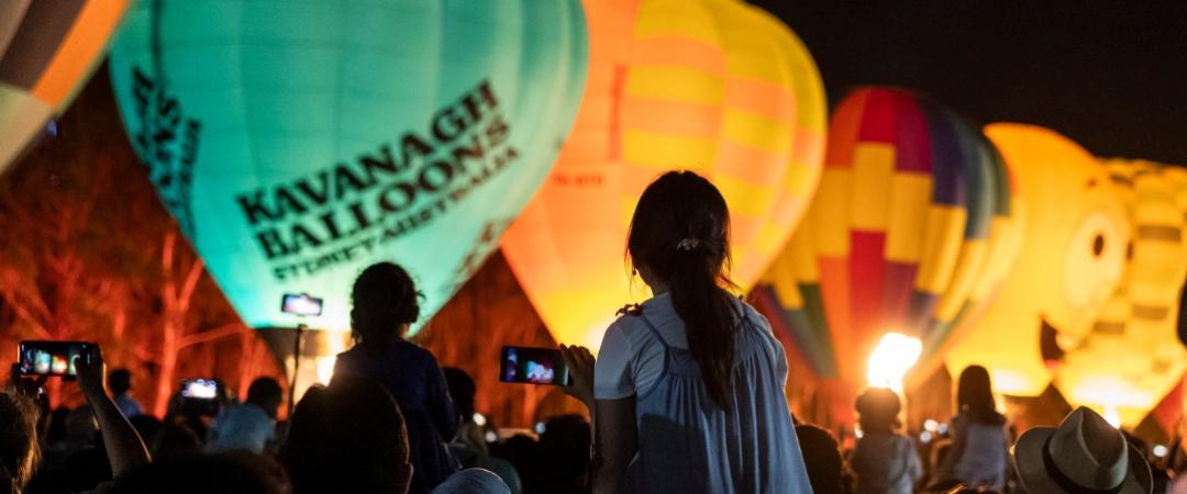 Silhouette of people looking at lit uphot air balloons