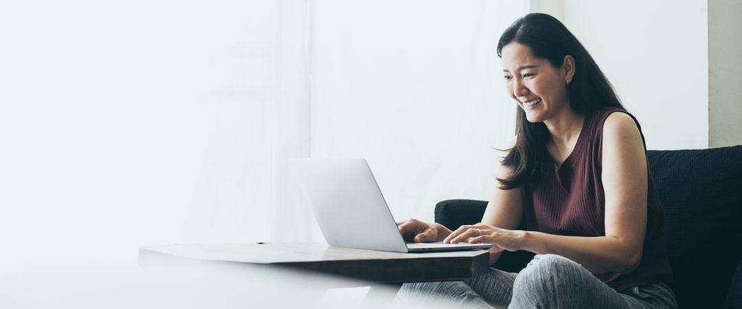 Women sitting on couch smiling at computer
