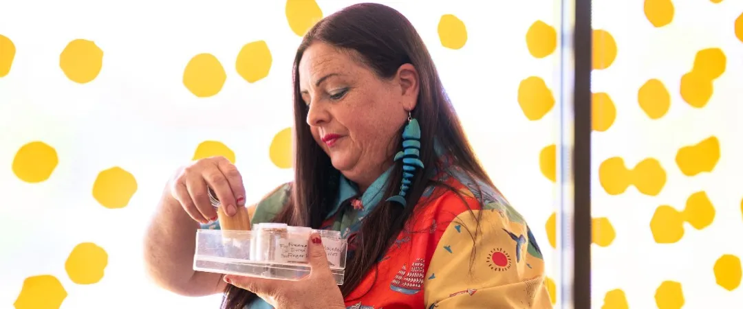 Woman in front of window looking through a small tub of native spices