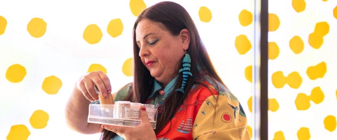 Woman in front of window looking through a small tub of native spices