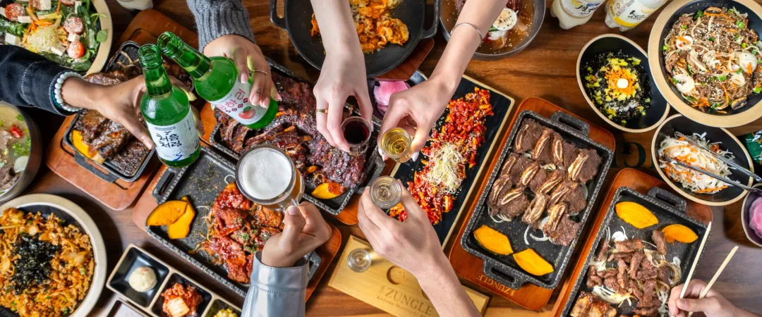 People cheersing over a table full of food