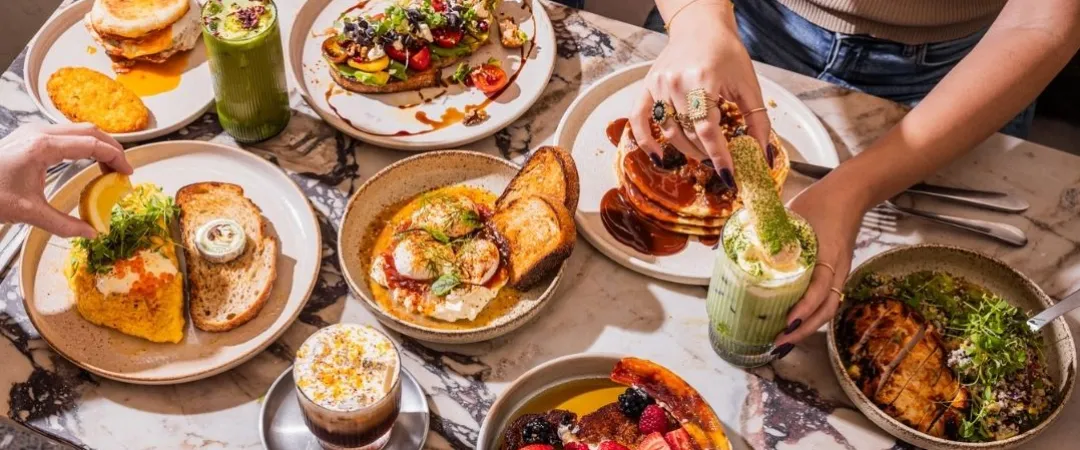 Table of yummy breakfast food like french toast, eggs, smashed avocado toast