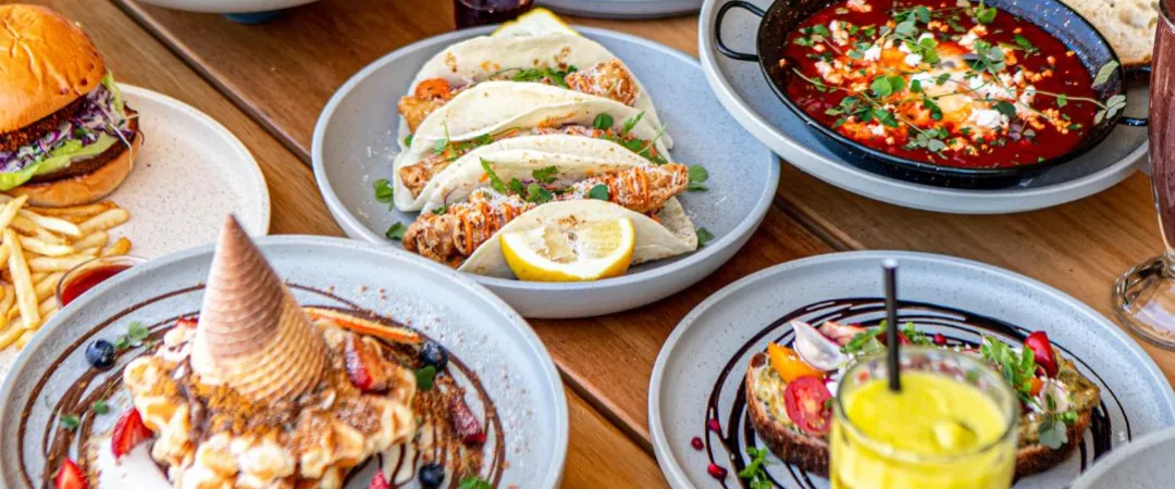 Tabe full of yummy plates of food like fish tacos, coconut french toast, eggs