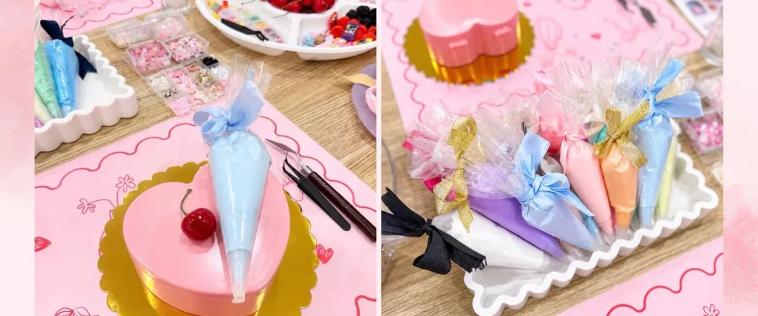 Pastel dessert display: pink heart-shaped cake with blue frosting and cherry, alongside colorful wrapped sweets on a white tray.