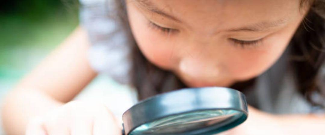 Girl looking through magnifying glass at a bug