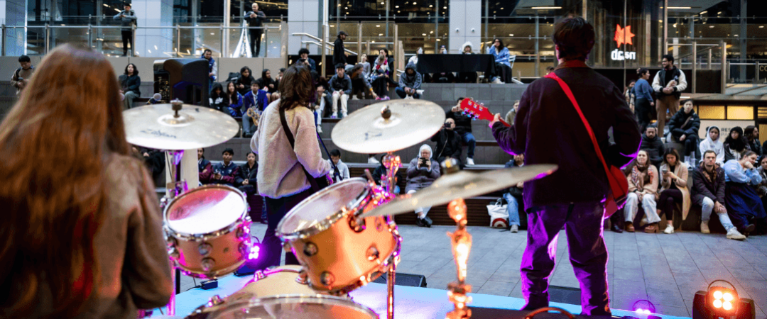 View of Parramatta Square from behind drumkit with two guitarists