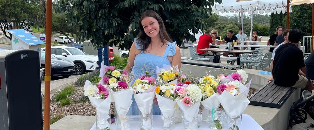 Smiling woman standing in front of a stall of market flowers