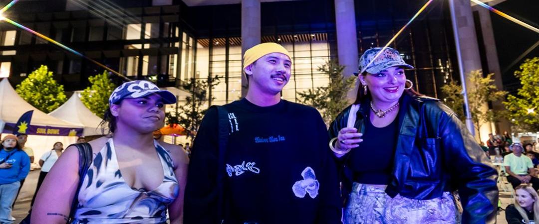 A group of 3 people in purple lighting