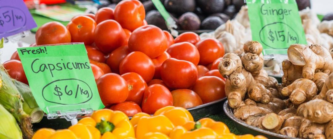 Table of brightly coloured fruit and vegetables like yellow capsicums, red tomatoes 