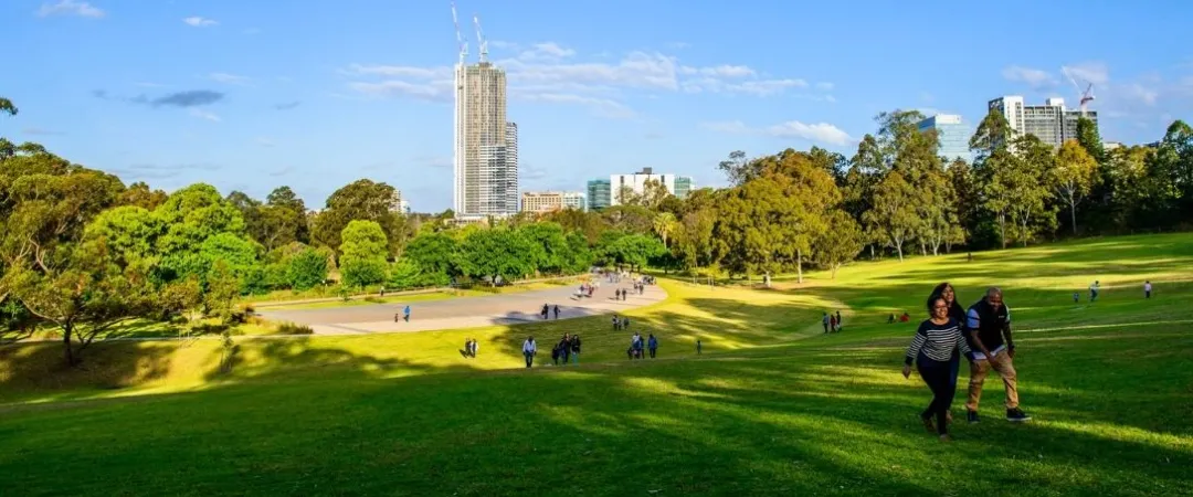 People enjoying grass area of Parramatta Park at the Crescent