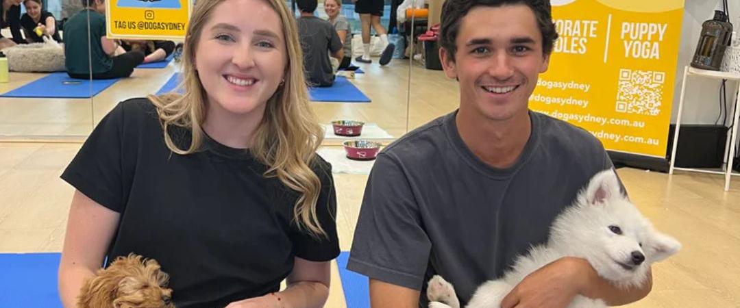 Man and woman smiling while holding small fluffy puppies