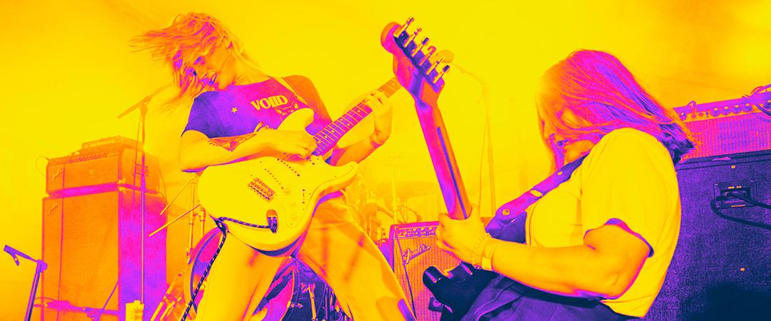 2 people playing guitar with yellow and purple glow