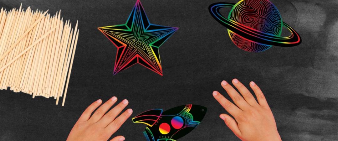 Hands on desk with black top, scratch artwork with space theme