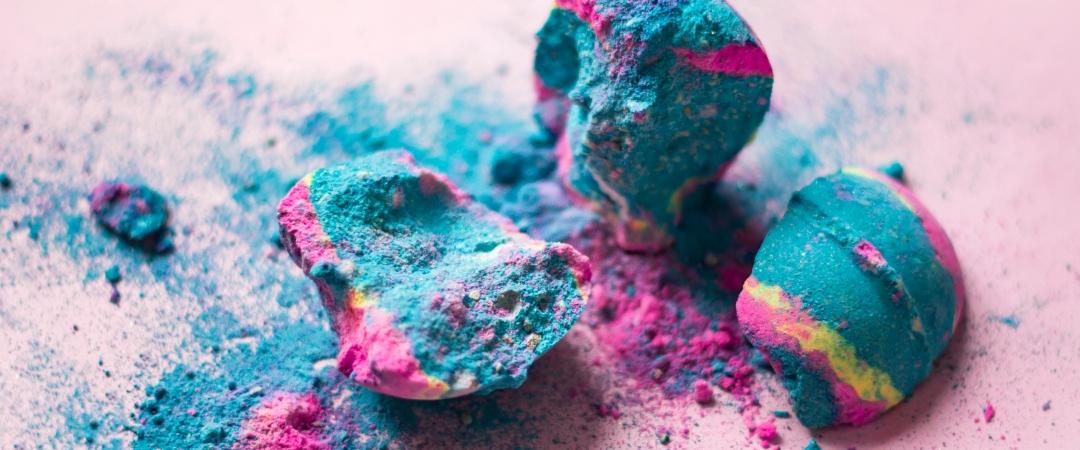 Broken colourful bath bombs on pink background