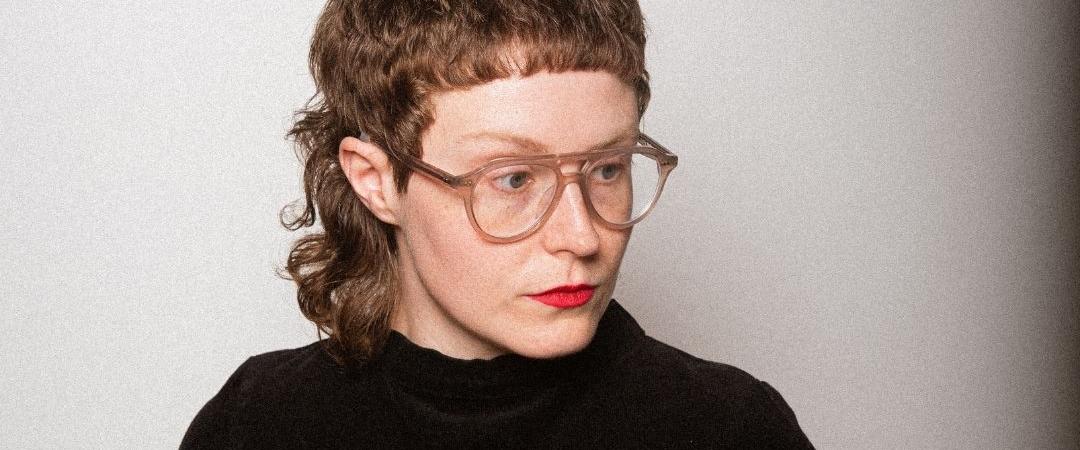 person with glasses looking over shoulder wearing a black top