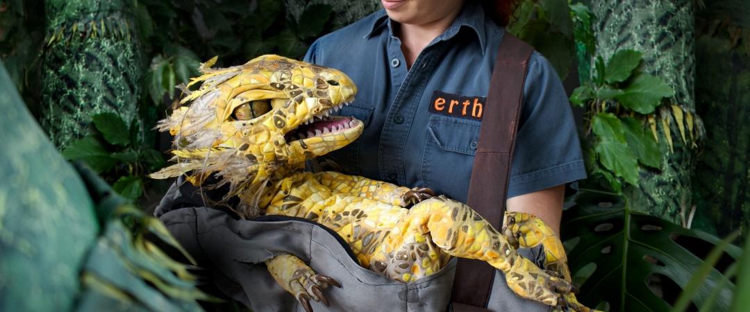 Woman in blue shirt holding dinosaur puppet