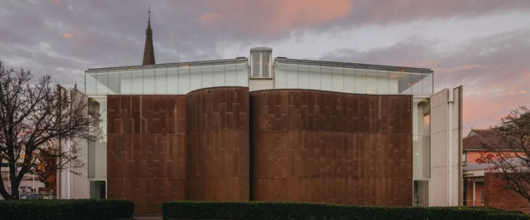 brown brick wall, with a steeple coming out over the top in the background