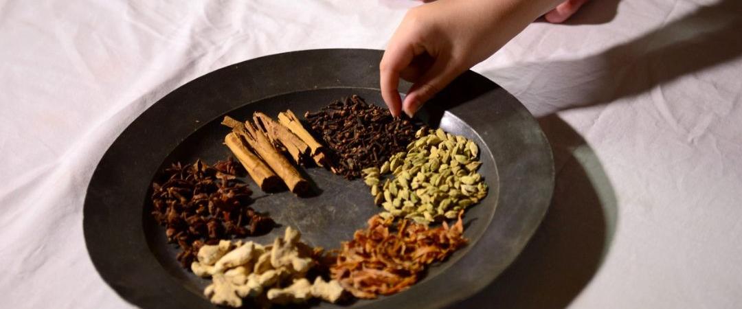 Hand picking up cardamom pods on a old old metal plate